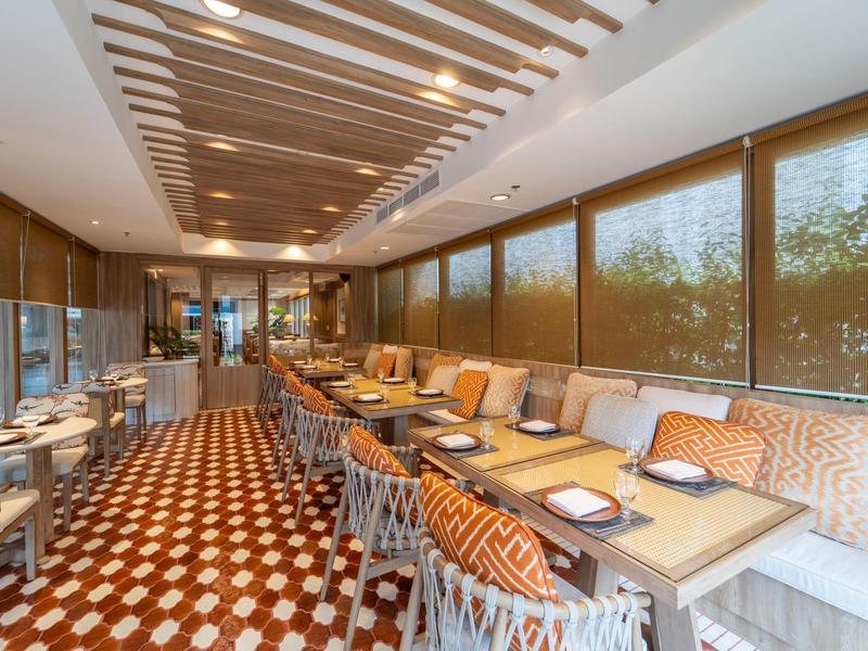 Moderner Hotelrestaurantbereich mit Holzdecke und großen Fensterfronten.