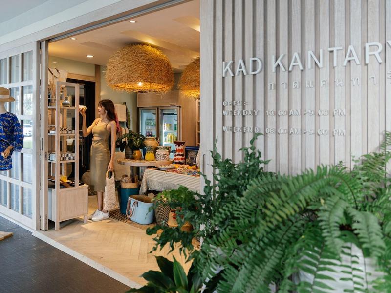 Eingang zu einem Hotel mit Pflanzen und offenem Tor, Gäste betreten den Empfangsbereich.