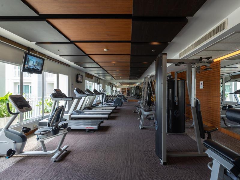 Moderner Fitnessraum mit Cardio-Geräten und spiegelnder Wand in hellem Ambiente.