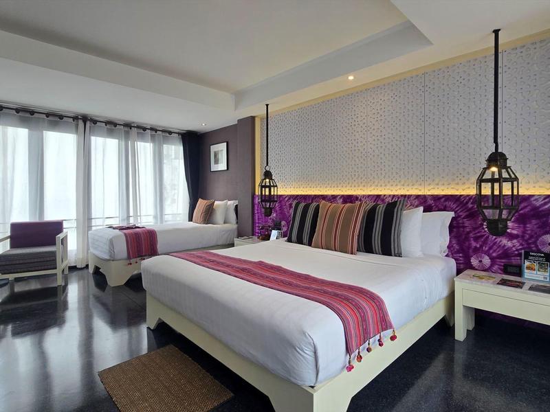 Modernes Hotelzimmer mit großem Bett, violetten Akzenten und Panoramafenstern.