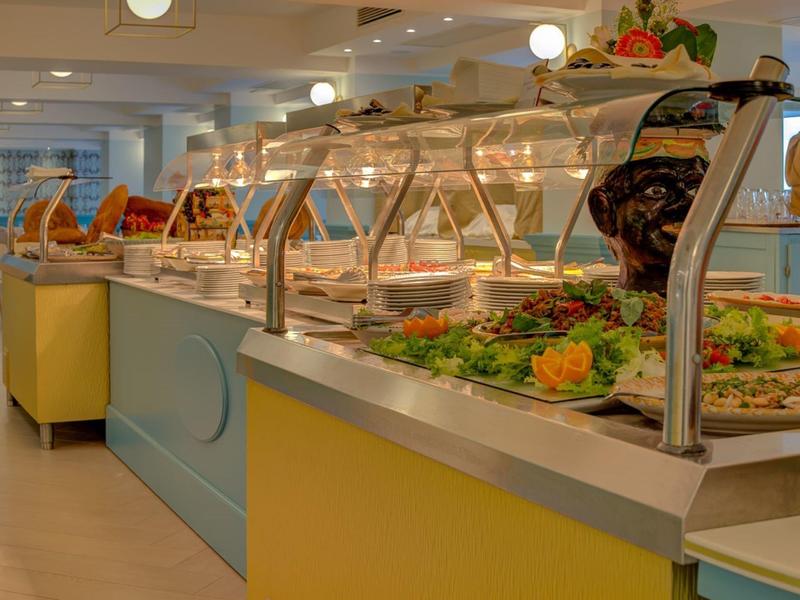 Buffet mit weitem Edelstahlbedienungstresen, bunter Salat- und Gemüseauslage, hellem Innenraum.