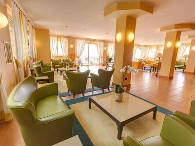 Helles, gemütliches Wohnzimmer mit grünen Ledersesseln, großem Tisch und warmem Holzboden.