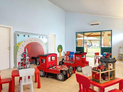 Hell eingerichteter Spielbereich mit roten Möbeln und verschiedenen Spielzeugen in einem Hotel.