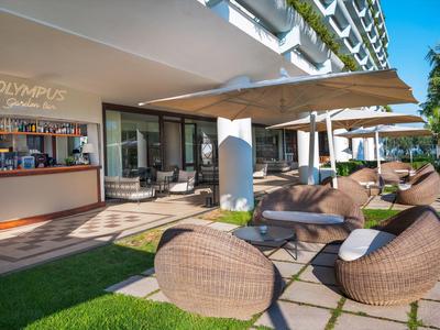 Moderner Außenbereich eines Hotels mit Lounge-Möbeln und Sonnenschutz unter Balkonreihen.