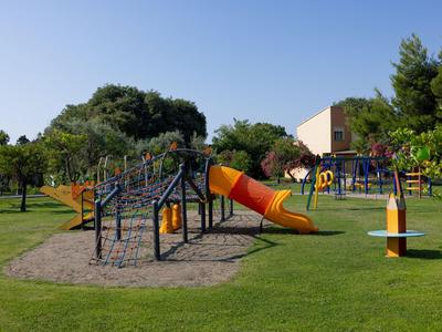 Spielplatz mit Rutsche und Klettergerüst auf grünem Rasen unter blauem Himmel