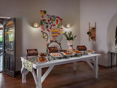 Tisch mit verschiedenen Frühstücksangeboten in einem Hotelrestaurant mit bunter Wandkunst.