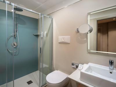 Modernes Badezimmer mit Glasdusche, weißer Toilette und Waschbecken.