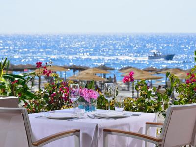 Terrasse mit gedecktem Tisch und Blick auf das Meer und Sonnenschirme am Strand.