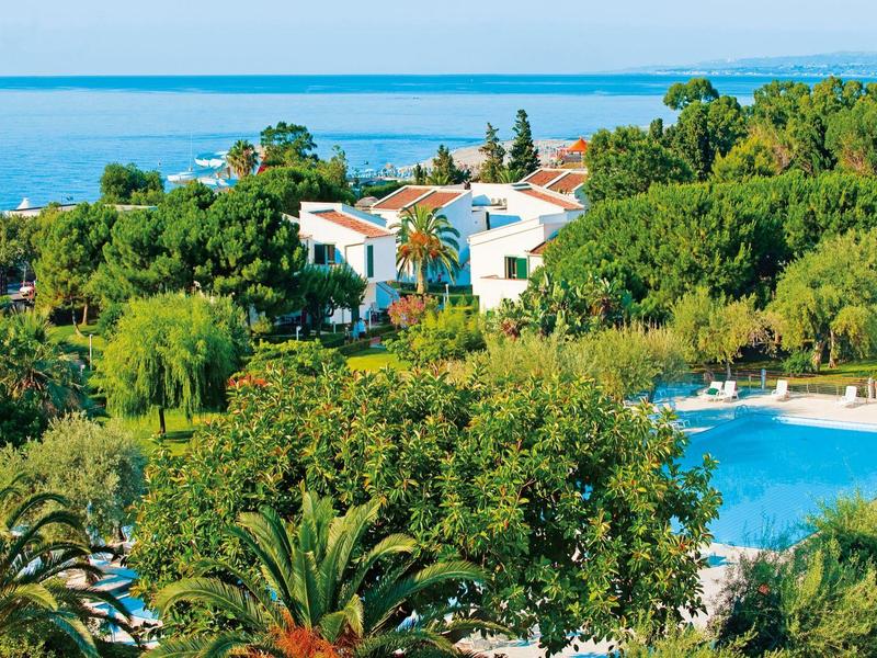 Moderne hotelreceptie met planten, een gebogen balie en slingerverlichting aan het plafond.