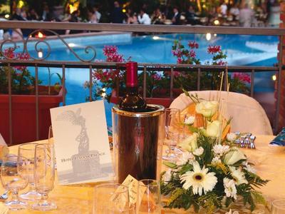 Mesa elegantemente puesta con flores y copas cerca de piscina iluminada de hotel por la noche.