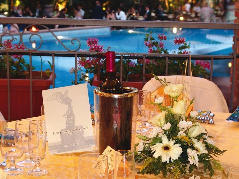 Mesa elegantemente puesta con flores y copas cerca de piscina iluminada de hotel por la noche.