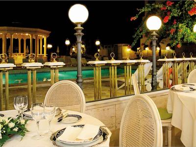 Elegantes Abendessen im Freien mit Blick auf beleuchteten Pool und Garten