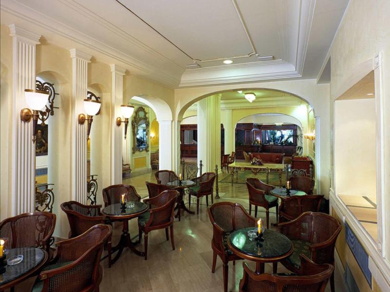 Eleganter, gemütlicher Gastraum mit Rundtischen, antiken Stühlen und warmen Wandleuchten.