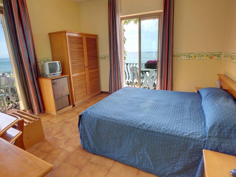 Bright hotel room with double bed and balcony overlooking the sea.