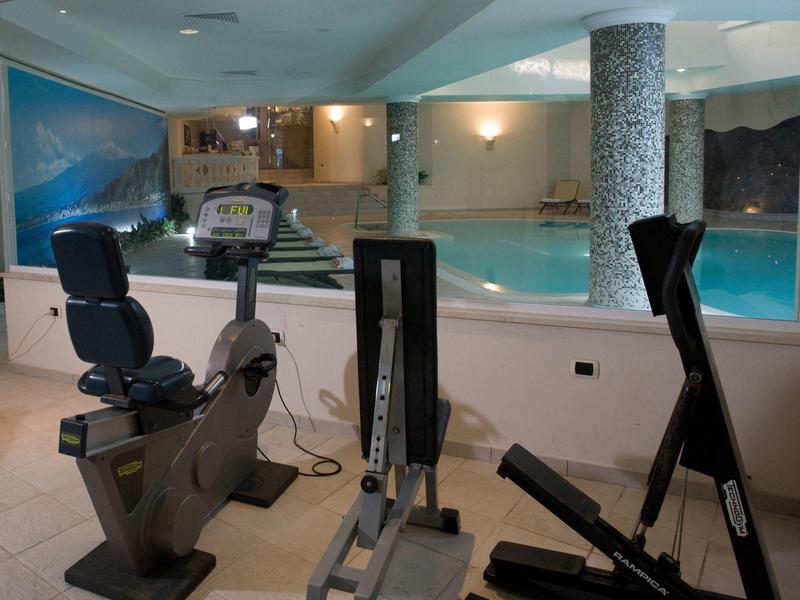 Appareils de fitness à l'intérieur à côté d'une piscine avec des colonnes.