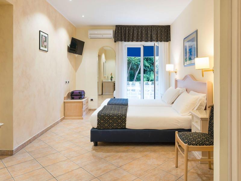 Chambre d'hôtel avec lit double, TV écran plat, balcon et décoration claire.