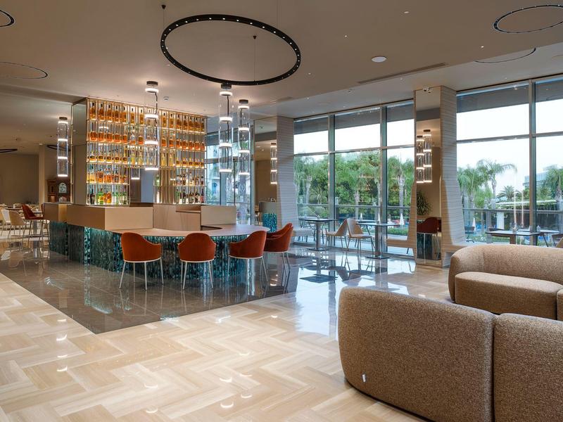 Bar d'hôtel moderne avec des sièges et de grandes fenêtres donnant sur l'extérieur.