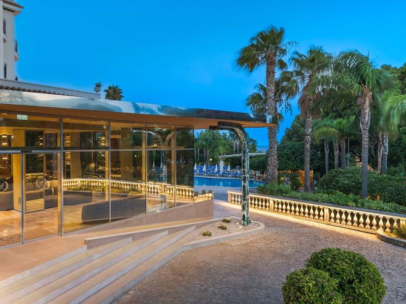 Vue du soir d'un hôtel moderne avec terrasse et palmiers au bord de l'eau