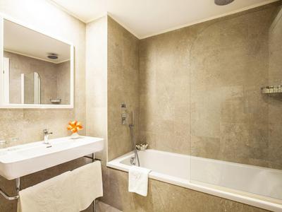 Bright bathroom with bathtub, sink, and mirror in neutral tones.