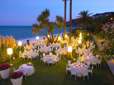 Abendliche Gartenparty am Meer mit stimmungsvoller Beleuchtung und gedeckten Tischen.