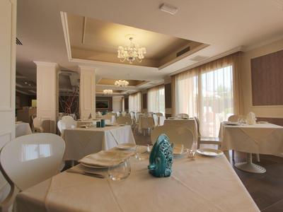 Bright and elegant hotel dining room with set tables and large windows.