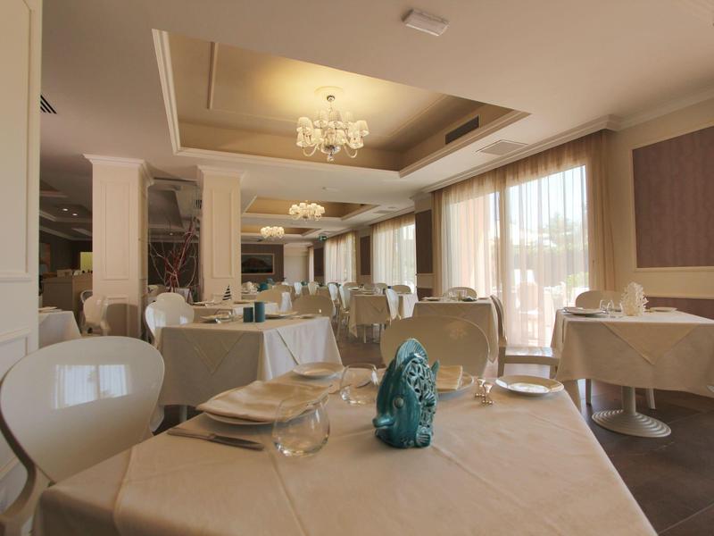 Bright and elegant hotel dining room with set tables and large windows.