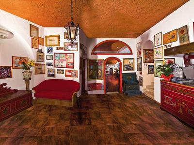 Gemütliches Zimmer mit roten Möbeln, holzvertäfelter Decke und zahlreichen gerahmten Bildern an den Wänden.