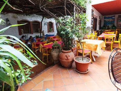 Przytulny taras z kolorowymi stolikami i roślinami w restauracji hotelowej.