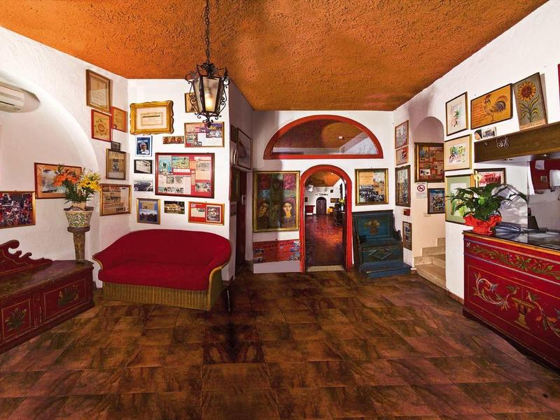 Przytulna lobby hotelowa z drewnianym sufitem, antycznymi meblami i licznymi ramkami na ścianach.