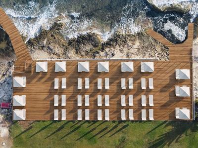 Vue aérienne d'une promenade de plage avec parasols et chaises longues au bord de la mer.