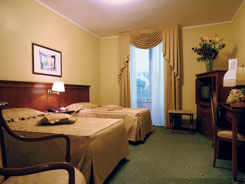 Pokój dwuosobowy z drewnianymi meblami, zasłonami i miękkim oświetleniem w hotelu.