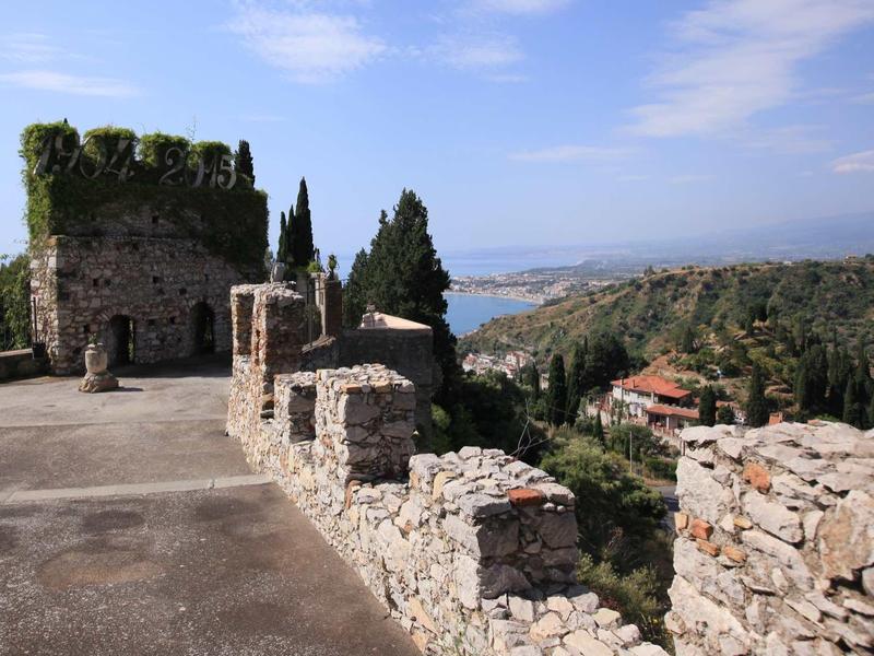 Widok ze starego kamiennego muru na zielone wzgórza i morze pod czystym niebem.