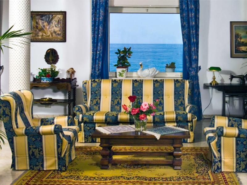 Salon z pasiaste sofy, drewnianym stołem i widokiem na morze przez okna.