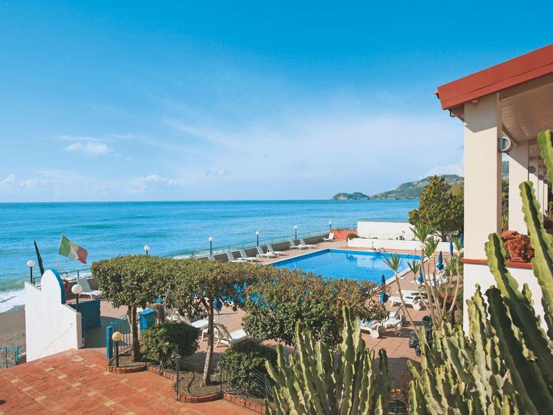 Taras hotelowy z basenem i widokiem na ocean pod niebieskim niebem.