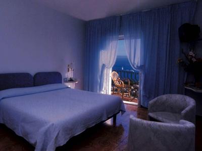 Slaapkamer met blauwe muren, bed en zitmeubilair, uitzicht op balkon 's nachts