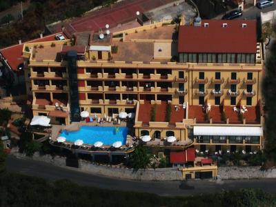 Luftaufnahme eines mehrstöckigen Hotels mit blauem Pool und umliegender Vegetation.