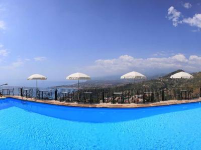 Groot buitenzwembad met uitzicht op bergen en lucht, omgeven door een terras.