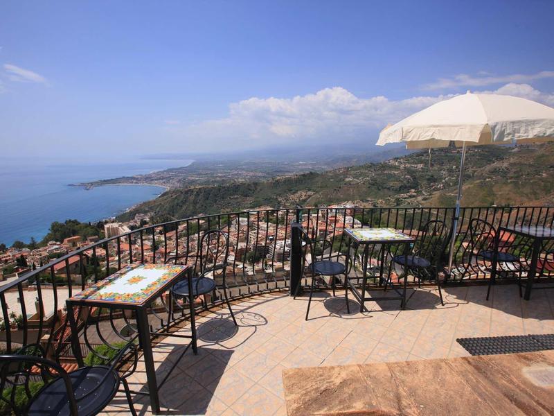 Terras met tafels en stoelen met uitzicht op de kustlijn en zee op een zonnige dag