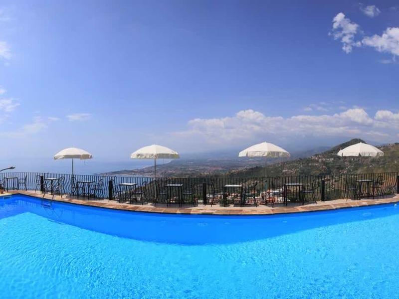 Groot buitenzwembad met uitzicht op bergen en lucht, omgeven door een terras.