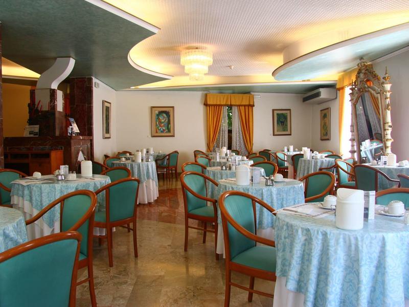 Elegant bright dining room with round tables and green chairs in a hotel.