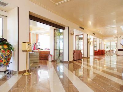 Licht verlichte hotelgang met glanzende marmeren vloer en decoratieve planten.