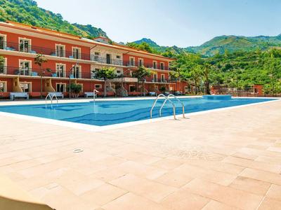 Hotel met groot zwembad en bergen op de achtergrond bij zonnig weer