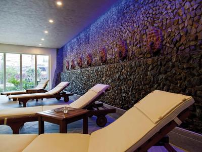 Moderner Ruheraum mit Holzbänken, entspannter Beleuchtung und dekorativer Steinwand.