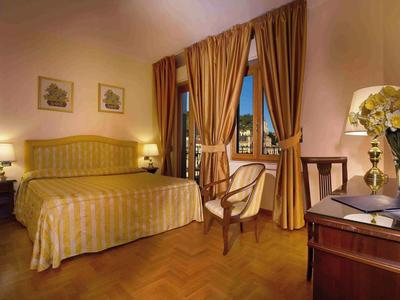 Cozy hotel room with double bed, chairs, and nighttime balcony view.