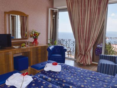 Cozy hotel room with two beds, balcony, and sea view.