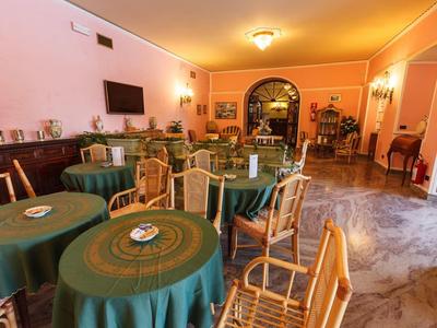 Cozy breakfast room with green tablecloths, wooden chairs, and warm lighting.