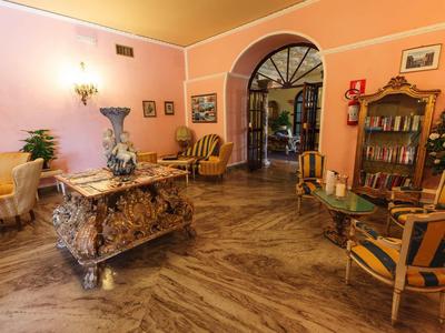 Elegant hotel room with historic dresser, chairs, and detailed floor design.
