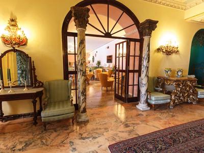 Elegant hotel lobby with antique furniture, columns, and warm lighting.