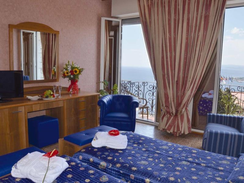 Cozy hotel room with two beds, balcony, and sea view.