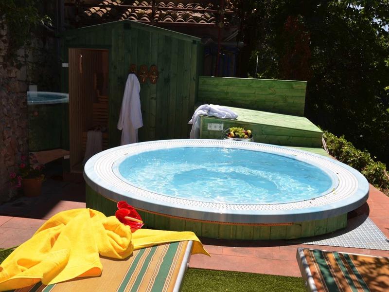 Outdoor round hot tub with water, surrounded by lounge chairs and towels.